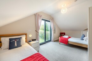 A bedroom with a bed, a bedside table, a lamp, a chair, and a window with curtains. - 6 Bed in Woolacombe (oc-mouro) (Woolacombe)