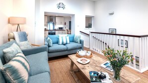 A modern living room with a sofa, coffee table, and a view into the kitchen.