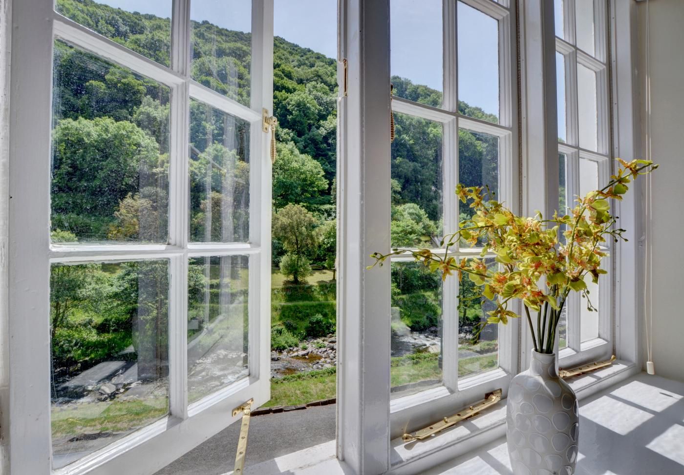 A room with large windows offering a view of a lush green landscape and a river.