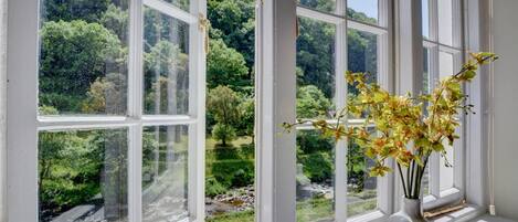 A room with large windows offering a view of a lush green landscape and a river.