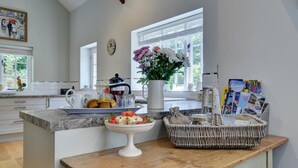 A kitchen with a coffee maker, a fruit bowl, a wicker basket, and a clock on the wall. - 4 Bed in Lynmouth (oc-marins) (Barbrook)