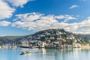 A coastal town with a hilltop settlement, calm water, and a small boat.