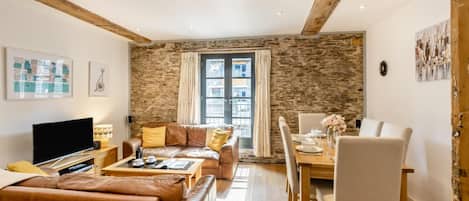 Un salon comprenant un canapé, une table basse, un téléviseur et un coin repas avec une table et des chaises.
