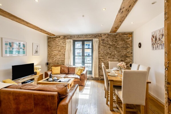 A living room with a sofa, a coffee table, a TV, and a dining area with a table and chairs.