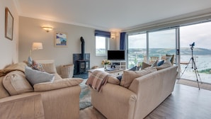 Un salon comprenant un ensemble de canapés, un téléviseur, une cheminée et un balcon avec vue.