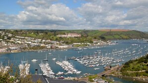 Un port de plaisance où de nombreux bateaux sont amarrés, entouré d’une ville avec des maisons et un grand bâtiment en arrière-plan.