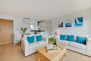 A modern living room with a sofa set, a coffee table, and a dining area with a chair and table.