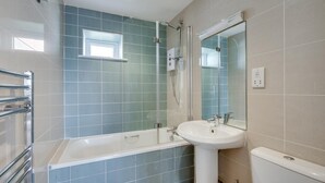 Une salle de bain avec une baignoire, un lavabo, une douche et une fenêtre.