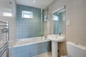 Ein Badezimmer mit Badewanne, Waschbecken, Dusche und einem Fenster.
