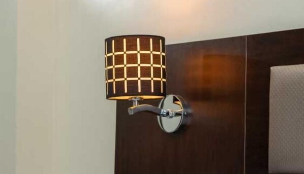 Una lámpara de pared con pantalla calada y base metálica.