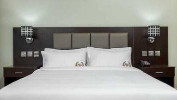 A hotel room with a large bed, two bedside tables, and a headboard with built-in lighting.