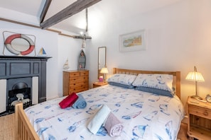 A bedroom with a bed, a dresser, a mirror, a fireplace, and a nightstand with a lamp. - 3 Bed in Torquay (oc-h75059) (Torquay)