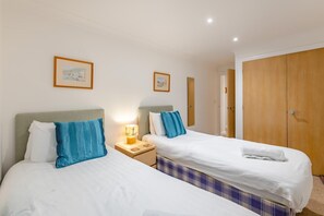 Ein Hotelzimmer mit zwei Betten, einem Holzschrank und einem Nachttisch mit Lampe.