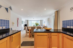 Eine moderne Küche mit Holzschränken, einer schwarzen Arbeitsplatte und einem Essbereich mit Tisch und Stühlen.