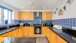 Uma cozinha moderna com armários de madeira, bancada preta e backsplash com azulejos azuis.