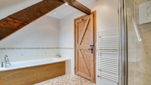 A bathroom with a wooden door, a bathtub, a shower area, and a tiled floor. - 2 Bed in Exminster (oc-h28725) (Exminster)