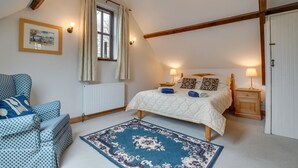 A bedroom with a bed, two bedside tables, a chair, a window with curtains, a radiator, and a ceiling with exposed beams. - 2 Bed in Exminster (oc-h28725) (Exminster)