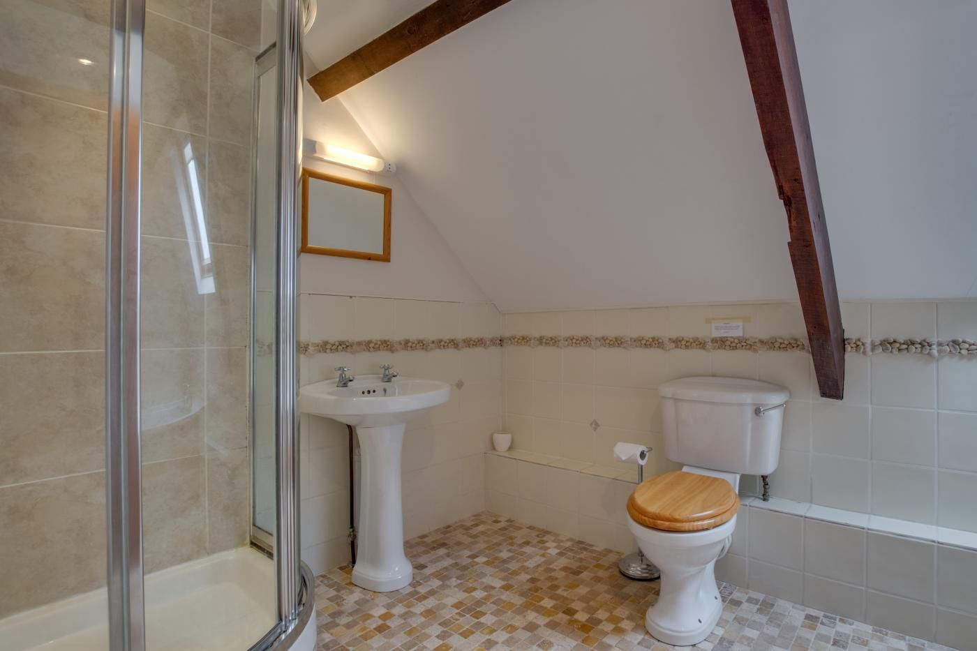 Une salle de bain avec douche, lavabo, toilettes et un sol carrelé.