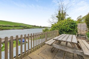 A riverside picnic area with a wooden fence, a bench, and a view of boats on the water. - 4 Bed in Frogmore (oc-bc721) (Frogmore)