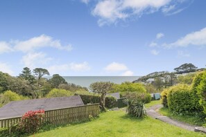 A coastal property with a grassy yard, a wooden fence, and a view of the sea.