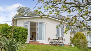 Een gelijkvloers huis met een terras, een eettafel en stoelen.