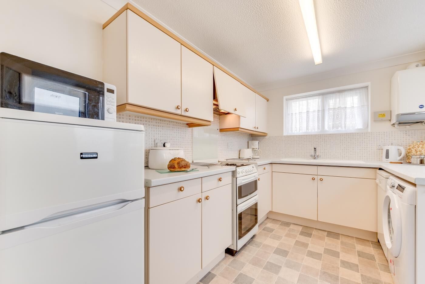 A compact kitchen with a refrigerator, oven, microwave, and a washing machine.