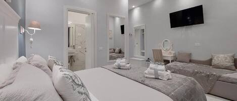 A modern bedroom with a large bed, two smaller beds, a TV, and a mirror.