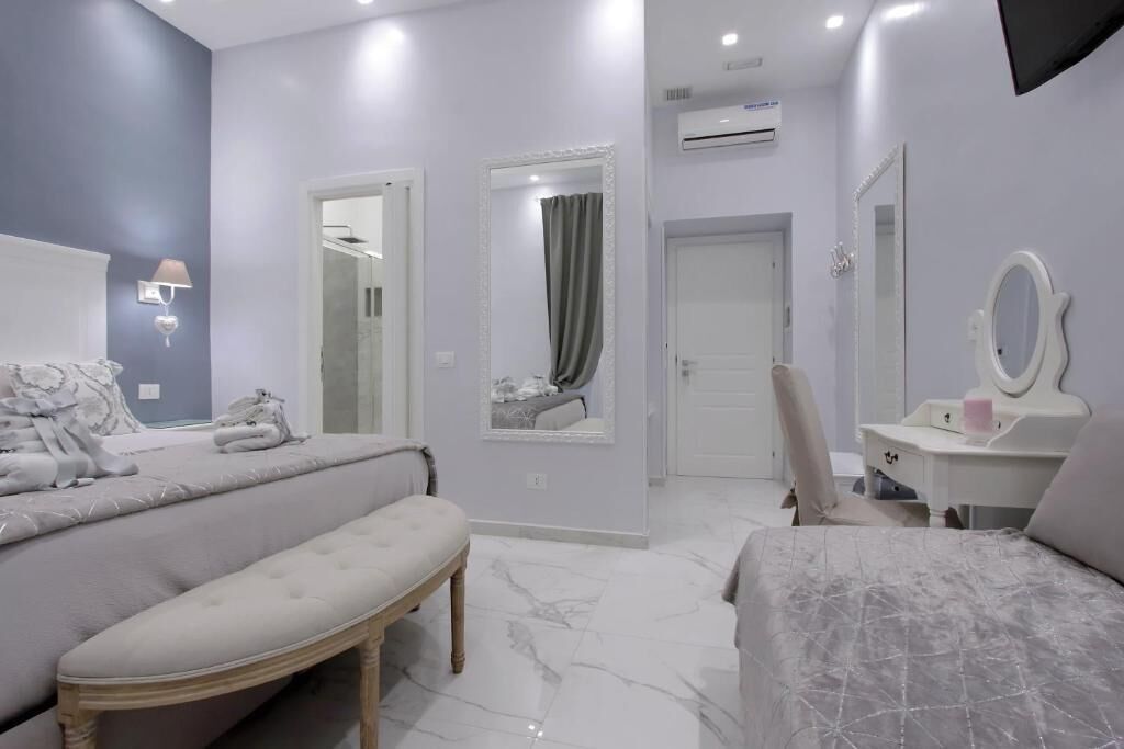 Un dormitorio moderno con cama, banco, tocador y espejo.