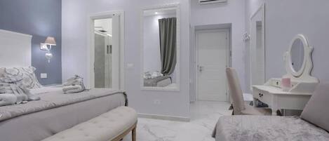 Un dormitorio moderno con cama, banco, tocador y espejo.