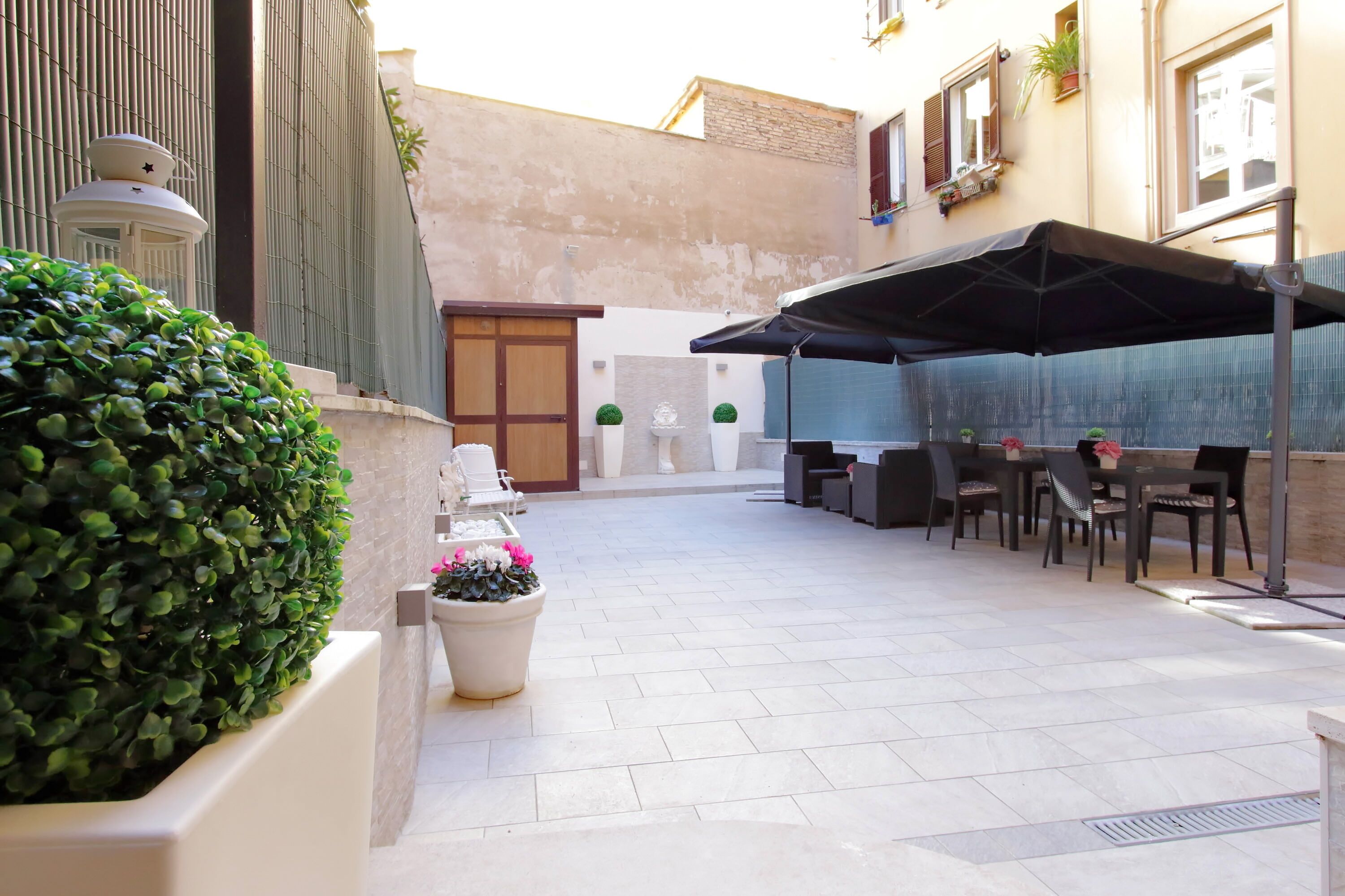 A courtyard with a seating area, potted plants, and a decorative wall.