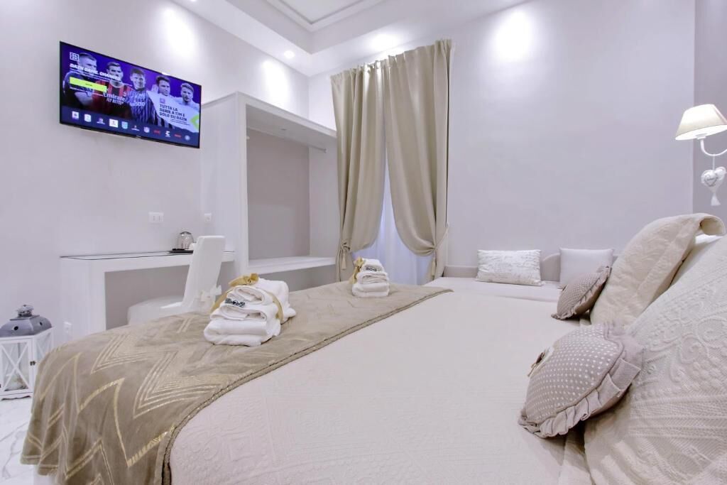 A hotel room with a large bed, a desk, a television, and a bathroom.