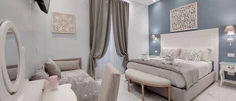 A modern bedroom with a large bed, bedside tables, a vanity with a mirror, and a TV mounted on the wall.