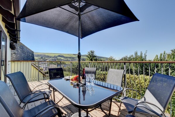 An outdoor dining area with a table, chairs, and a large umbrella.