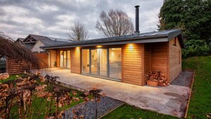 Ein modernes Haus mit großem Glasflurtür, Schornstein und einem gepflegten Garten.