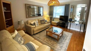 A living room with a sofa, coffee table, TV, and a fireplace. - 2 Bed in Torquay (oc-bemews) (Torquay)