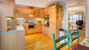 A compact kitchen with wooden cabinets, a built-in oven, and a microwave. - 2 Bed in Torquay (oc-bemews) (Torquay)