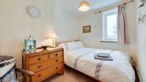 A bedroom with a bed, a wooden dresser, a lamp, a window with curtains, and a wall-mounted picture. - 2 Bed in Shaldon (oc-starco) (Shaldon)