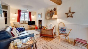 A living room with a leather sofa, a wooden chair, a television, a fireplace, and a star decoration on the wall. - 2 Bed in Shaldon (oc-starco) (Shaldon)
