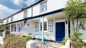 A white building with a blue door and a covered porch with blue chairs. - 2 Bed in Shaldon (oc-starco) (Shaldon)