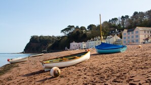 A sandy beach with several boats, a buoy, and buildings in the background. - 2 Bed in Shaldon (oc-stchco) (Shaldon)