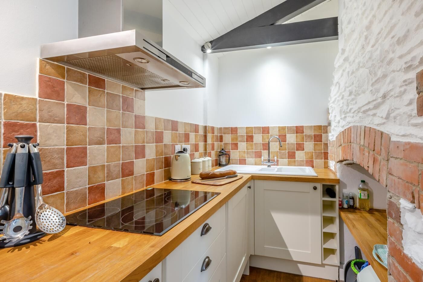 A kitchen with a stove, sink, and a brick oven.