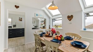 A modern kitchen with a skylight, a dining area with a wooden table, and a view of the outside. - 4 Bed in Shaldon (oc-driftc) (Shaldon)