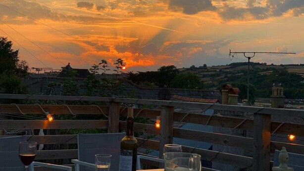 A sunset view from a terrace with wooden railings, a bottle of wine, and glasses on the table. - 4 Bed in Shaldon (oc-driftc) (Shaldon)