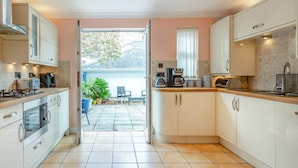 Een moderne keuken met witte kastjes, een inbouwoven en een koffiezetapparaat.