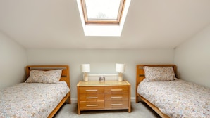 Een slaapkamer met twee bedden, een dressoir, een dakraam en een radiator.