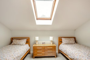 Ein Schlafzimmer mit zwei Betten, einem Schminktisch, einem Oberlicht und einer Heizung.