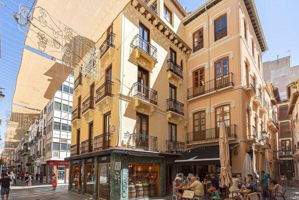 A street with buildings, shops, and outdoor seating areas.