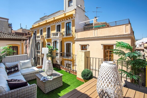 A courtyard with outdoor seating, a small garden, and a building with balconies.