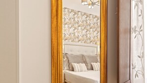 A bedroom with a large ornate mirror, a bed with a floral headboard, and a bedside lamp. - Genteel Home Mesones I (Granada)