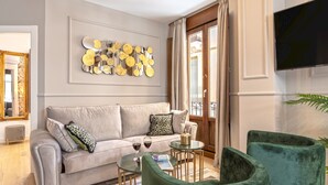 A living room with a grey sofa, green armchairs, a coffee table, and a decorative wall piece. - Genteel Home Mesones I (Granada)